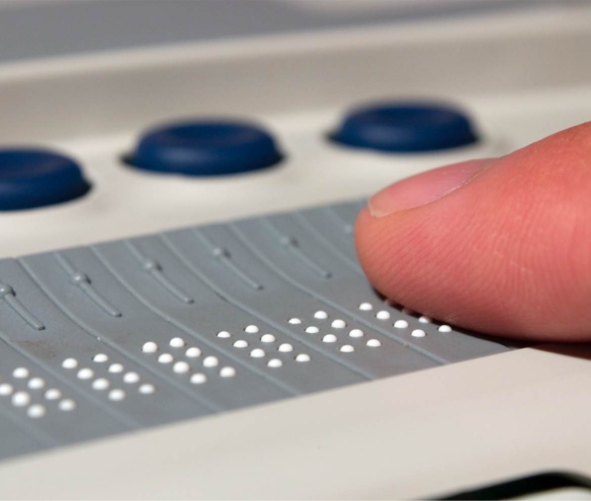 Finger reading braille text on a braille screen reader.