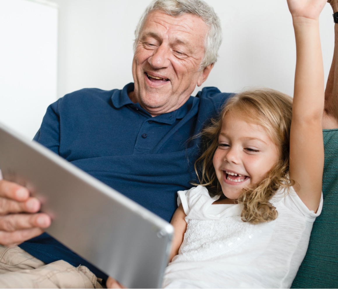 Grandfather and granddaughter having fun over a tablet.