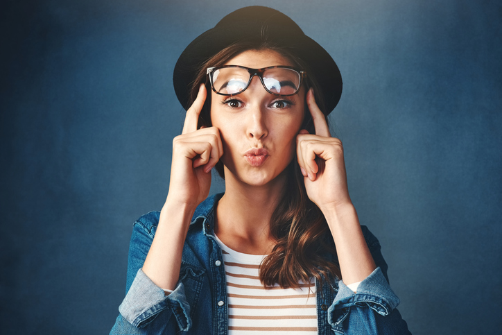 Pretty young woman with glasses on her forehead, pointing on her temples like she had a great idea.